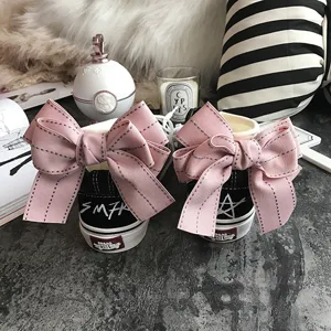 Black canvas sneakers featuring large pink bows on heels and stylish graffiti design.