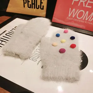 Grey fluffy rabbit hair mittens with colorful pom-poms, cute winter warm gloves detail.