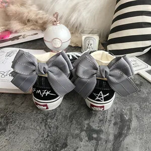 Fashionable black canvas shoes with large grey bow decor and unique back print, stylish sneaker.