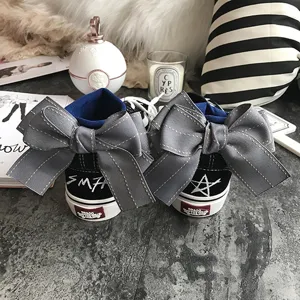 Black high-top canvas sneakers featuring large grey bow decoration, stylish and cute shoes.