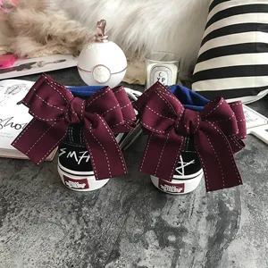 Black canvas low-top sneakers featuring large burgundy ribbon bows on the back heel design.