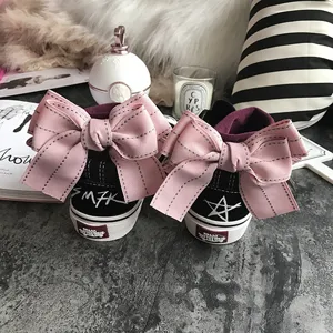 Detailed view of black canvas shoes featuring a large pink bow and graffiti heel design.