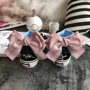 Black high-top canvas sneakers with oversized pink bow and graffiti for cute style.