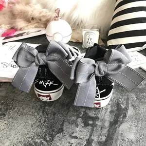 Black canvas sneakers with stylish grey bow knots, trendy streetwear design, comfortable flat shoes for women.