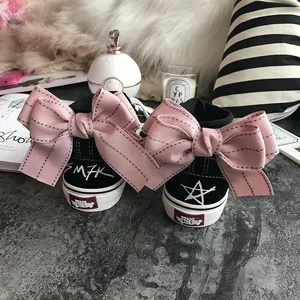 Black high-top canvas sneakers featuring large pink bow knots on the heel and stylish prints.