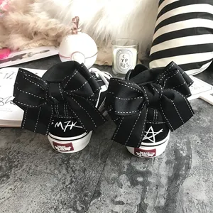 Detailed view of black high-top canvas sneakers featuring a large back bow and unique print.