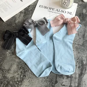 Close-up detail of cute light blue cotton socks featuring stylish ribbon bows on the back.