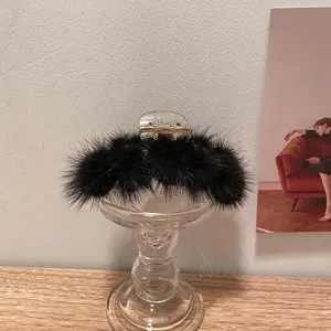 Vue détaillée de la grande pince à cheveux en fourrure de vison noire, design pelucheux élégant.