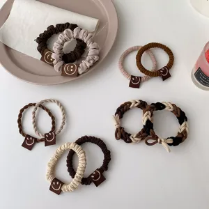 Vue détaillée de chouchous bruns mignons avec de petites étiquettes en cuir souriantes pour coiffure.