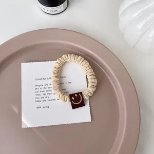 Vue détaillée d'chouchou beige mignon avec étiquette smiley marron, accessoire élastique.