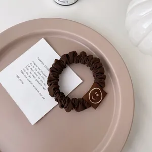 Chouchou de cheveux marron avec joli patch smiley élastique pour queue de cheval.