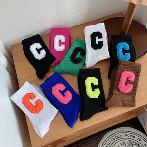 Nahaufnahme stylischer Baumwollsocken mit farbigen College-Buchstaben C-Aufnähern.