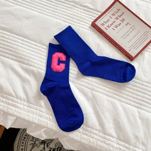 Detailansicht blauer Baumwollsocken mit rosa College-Buchstabe C Patch in Szene.