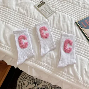 Chaussettes mi-hautes blanches avec écusson lettre C rose duveteux, tendance étudiante.