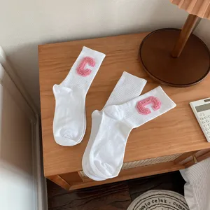 Chaussettes mi-hautes blanches avec écusson lettre C en bouclette rose, style quotidien.