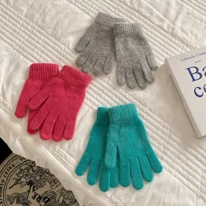 Detail shot of solid color knitted five-finger gloves in grey, pink, and teal for winter warm wear.