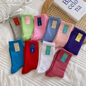 Gedetailleerd uitzicht van kleurrijke slouch sokken met schattige smiley stoffen labels.