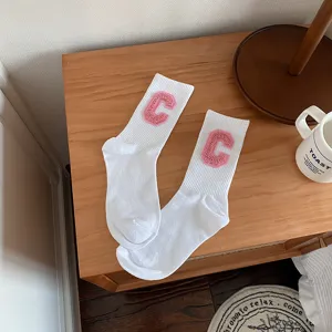 Chaussettes mi-hautes blanches avec écusson lettre C rose pelucheux pour look tendance quotidien.