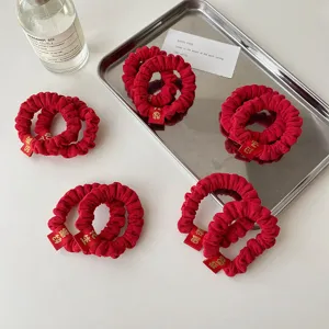 Red pleated hair scrunchies with festive embroidery tags, perfect New Year hair accessories.