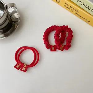 Detailed view of red pleated hair scrunchies and hair ties with festive tags on white table.