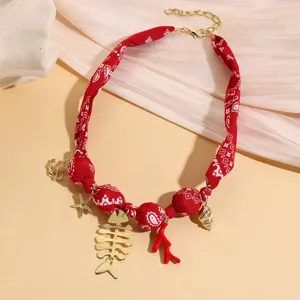 Resort style red paisley fabric necklace featuring gold-tone marine pendants like fish bone and starfish.
