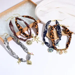 Detailed view of trendy fabric scarf necklaces featuring various metal charms and prints.