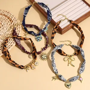 Detailed shot of trendy colorful printed scarf woven necklaces with diverse metal charms and pearls.