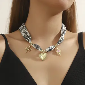 Close-up of stylish fabric scarf choker necklace with metallic star and heart charms detail.