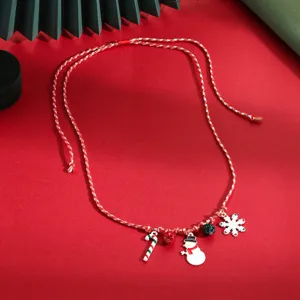 Christmas necklace detail showing festive snowflake and snowman pendants on braided red cord.