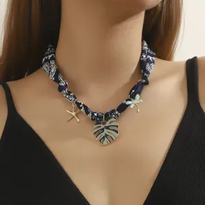 Chic navy blue bandana fabric necklace with tropical monstera leaf and starfish charms for women