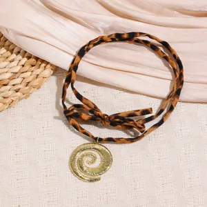 Leopard print fabric ribbon necklace with elegant gold tone swirl pendant and cute bow detail.