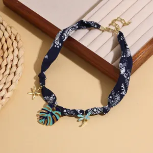 Detailed view of the blue printed fabric scarf necklace with gold charms and chic pendants.