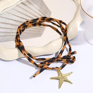 Close-up detail of leopard print fabric necklace with gold starfish pendant and bow.