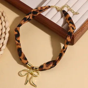 Leopard print fabric ribbon choker necklace featuring a stylish gold-tone alloy bow pendant.