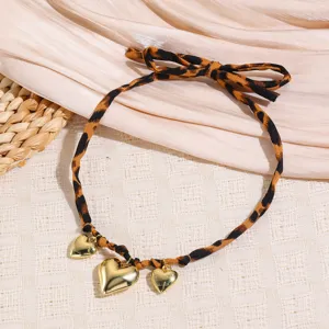 Detail shot of leopard print ribbon necklace with gold heart pendants and cute bow tie element.