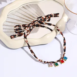 Leopard print scarf necklace detail view, featuring bow design and colorful crystal pendant charms.