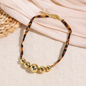 Close-up of a chic leopard print fabric choker necklace featuring stylish metallic gold spheres.