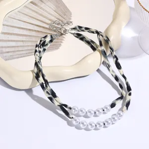 Detail view of double-layer necklace featuring leopard print ribbon and stylish white pearls.