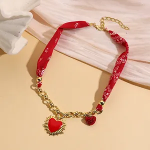 Close-up detail of the red fabric spliced gold chain necklace with heart pendant, stylish.