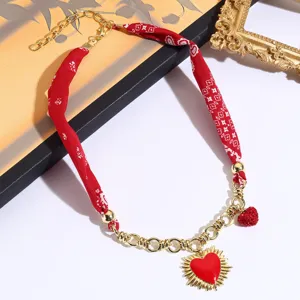 Exquisite red fabric scarf and gold chain necklace featuring a charming red heart pendant.