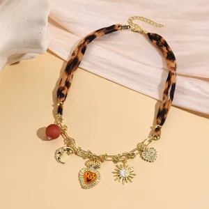 Close-up detail of the vintage leopard print scarf necklace with gold charms and pendant.