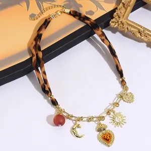 Close-up detail shot of the vintage leopard print silk scarf necklace with gold charms.