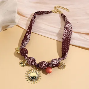 Vintage paisley fabric spliced necklace detail with sun pendant and chic metal charms.