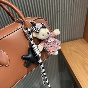 Primer plano detallado del tierno colgante de osito de peluche a cuadros en el bolso.