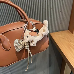 Cute fluffy dachshund plush bag charm with metallic heart pendant and leather braided strap detail.
