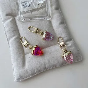 Strawberry keychain detail, cute bag charm with gold clasp and resin fruit pendant.