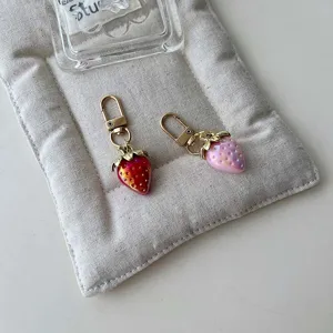 Close up detail of cute strawberry metal keychain charm with glossy finish and lobster clasp.
