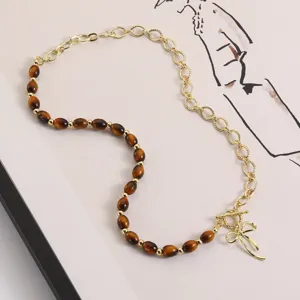 Retro brown beaded necklace detail view featuring gold chain link and bow pendant accessory