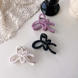 Matte hair claw clip detail showcasing elegant ribbon design in purple, black and white.