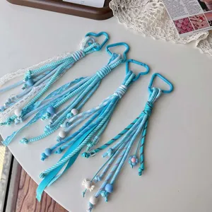 Close-up details of blue woven lanyard bag charm featuring lace ribbon and pretty beads.